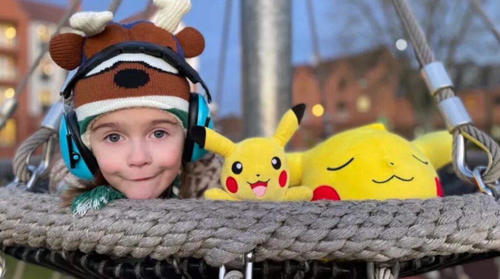 Young child sitting next to Pikachu stuffed animals